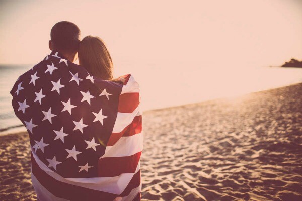 pareja con bandera de estados unidos en la playa