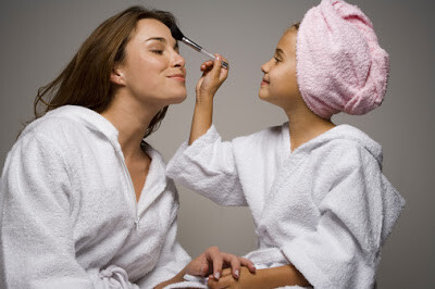 Girl (8-9) caressing mothers face with brush